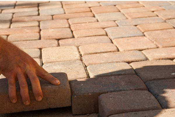 Handyman Relevelling And Relaying Red Pavers In An Outdoor Area